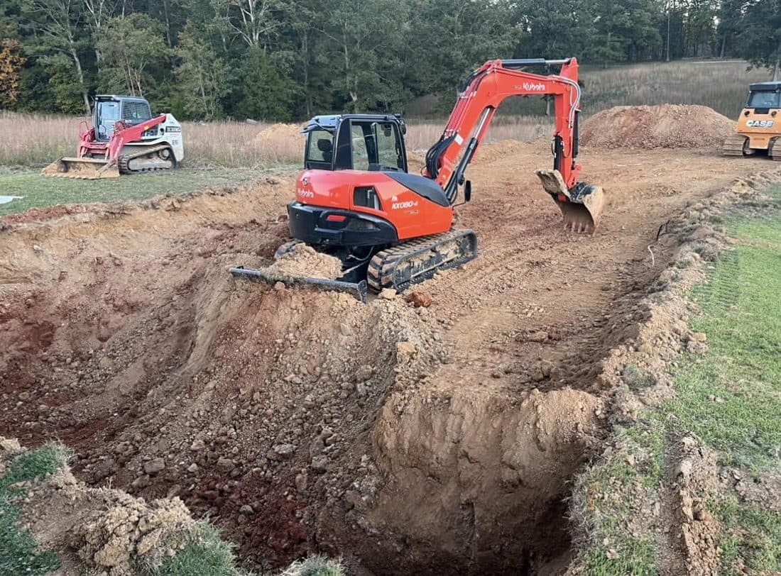 Excavator cutting a trench on a graded site