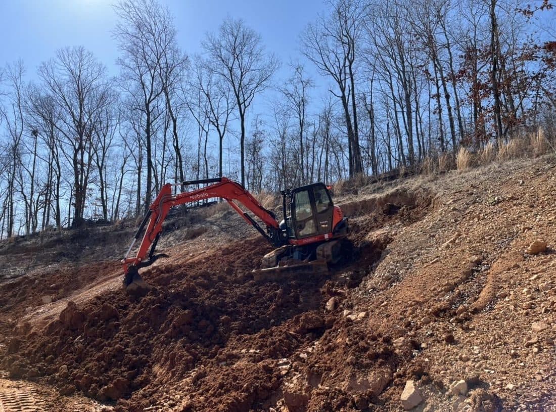Orange excavator working a fresh dirt pit